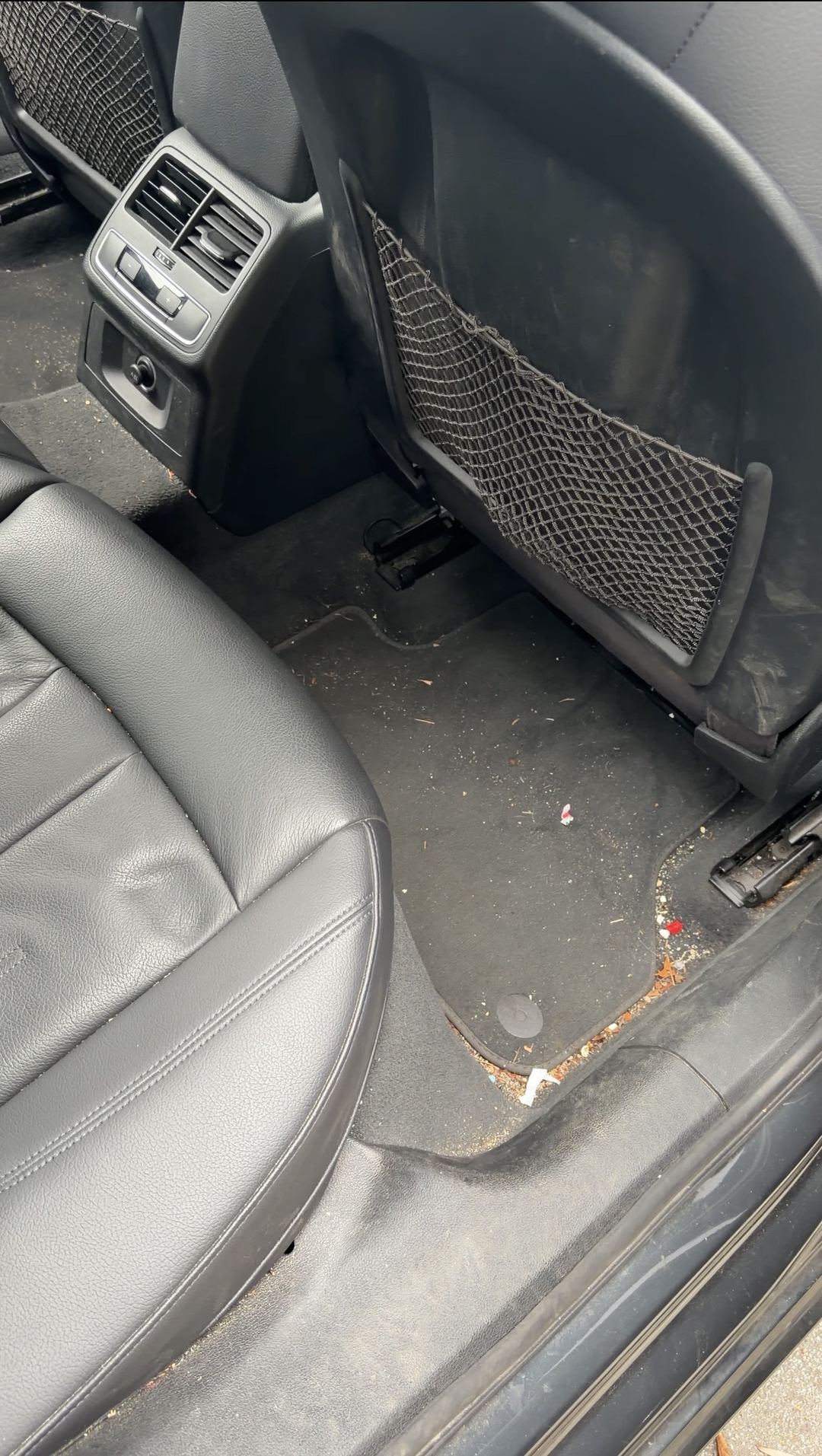 Grit, needles and wrapper bits on the rear floor mat behind the passenger seat of an Audi A4