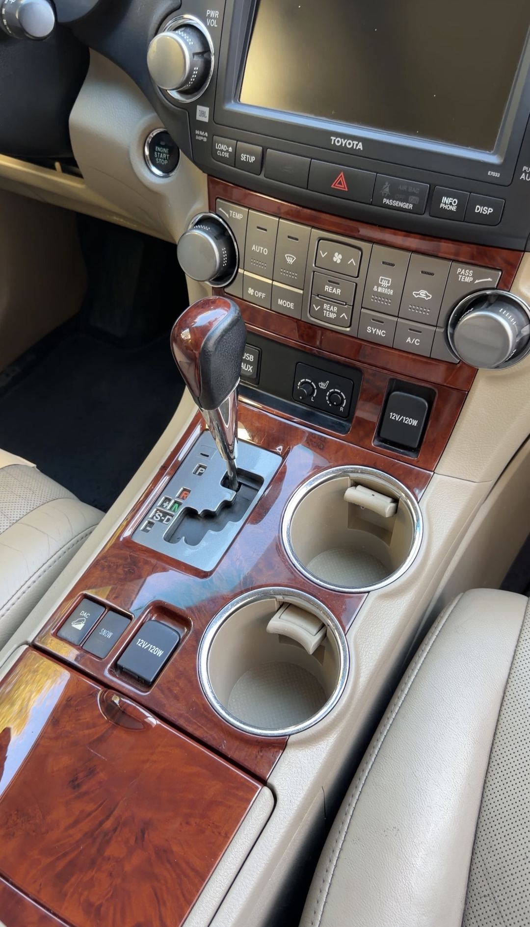 Clean wood-grain centre console and empty cupholders in a Toyota Highlander after detailing