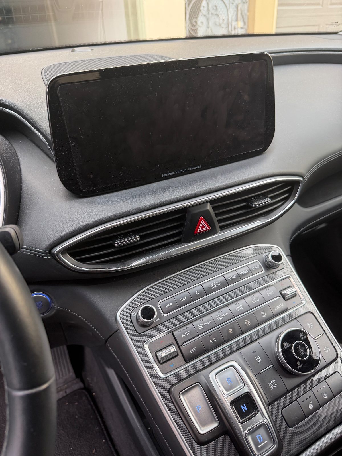 Infotainment screen and centre stack of a Hyundai Santa Fe before detailing, hazy with dust