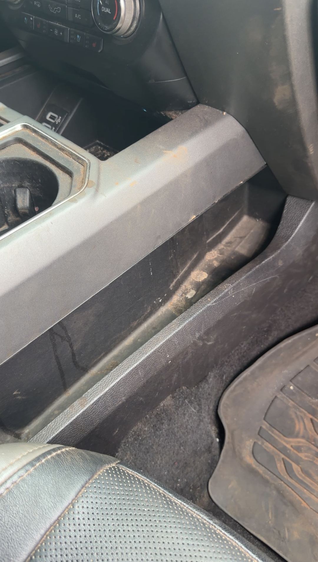 Grit along the console side and seat rail of a Ford F-150 Raptor before cleaning