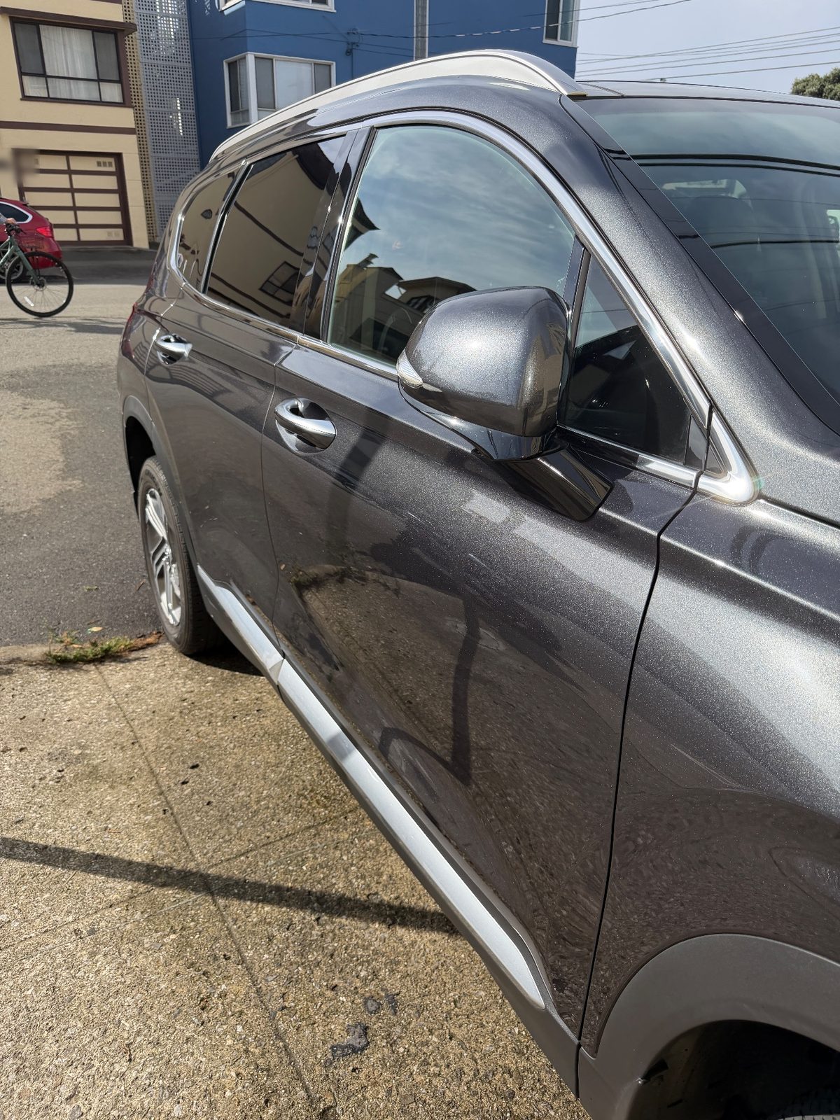 Passenger side of a clean dark grey Hyundai Santa Fe after detailing, with doors and mirror gleaming