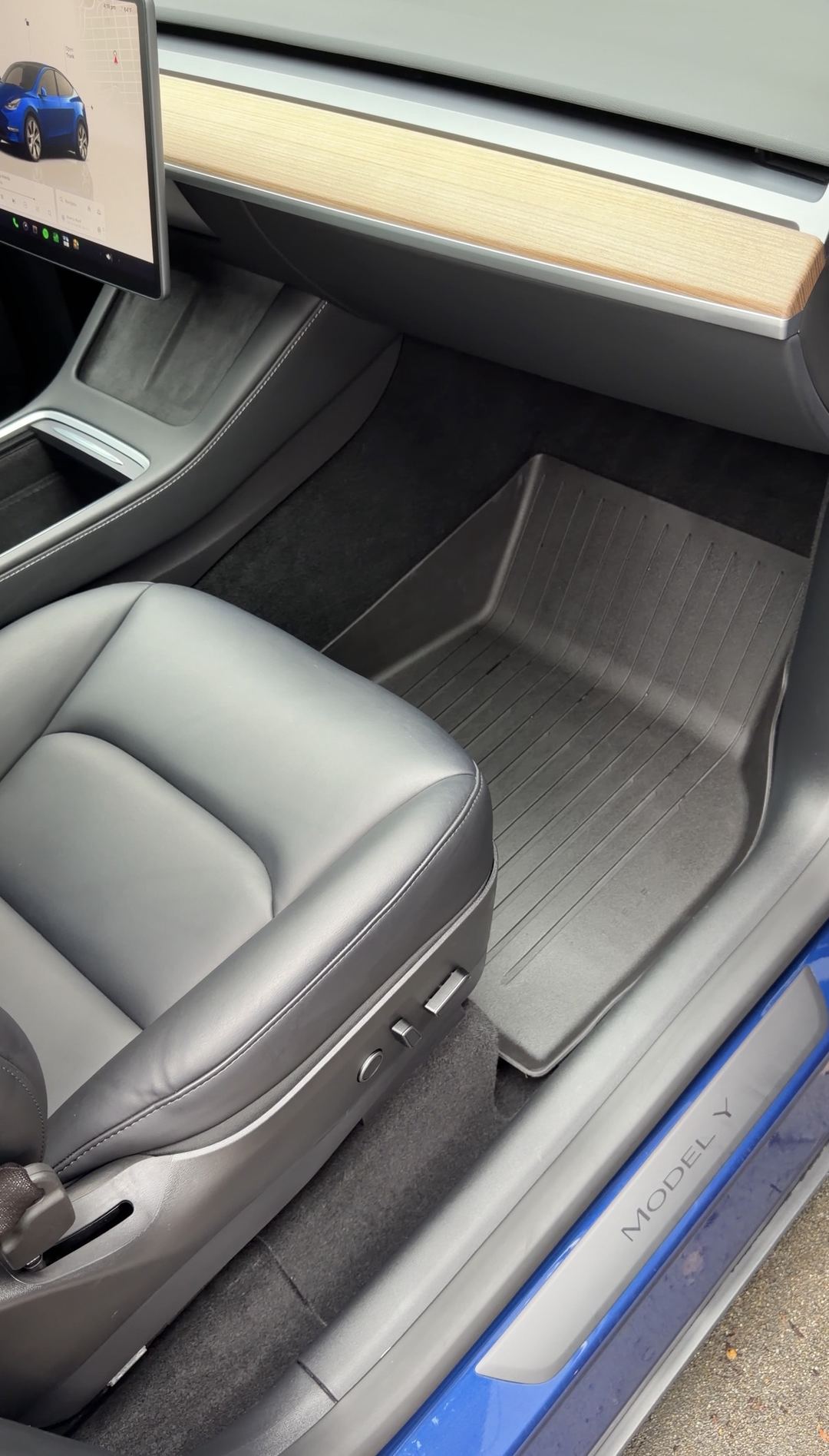 Clean front passenger footwell of a Tesla Model Y with the rubber floor liner refitted after detailing.