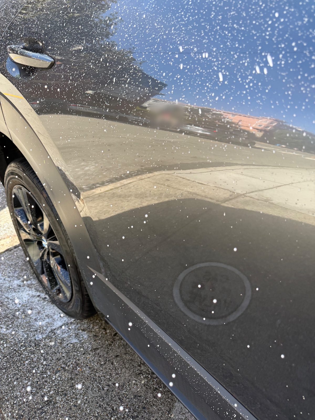 Side of a grey Mazda CX-30 during the wash, foam droplets and road film on the paint
