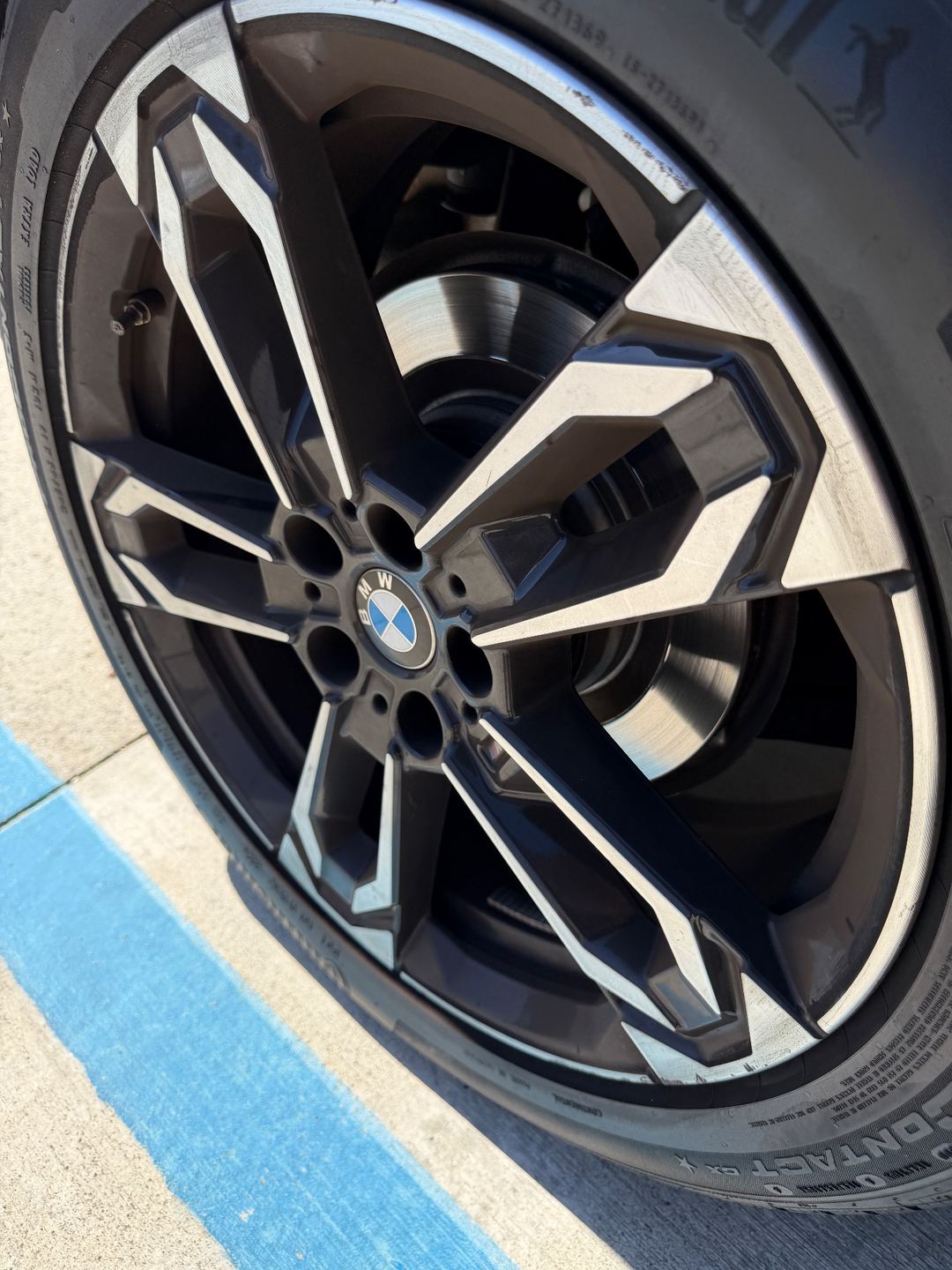 Rear wheel of a grey BMW X1 before detailing, with a dull brown tyre sidewall