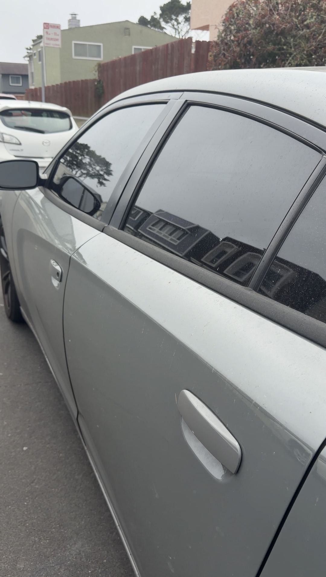 Dust and specks on a grey Dodge Charger's side glass and doors before cleaning
