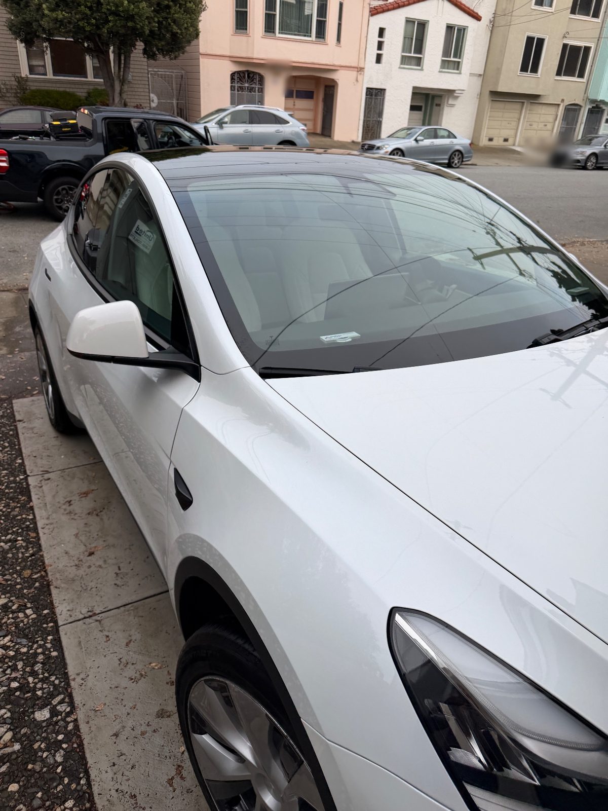 Front three-quarter view of a white Tesla Model Y after detailing, parked on a residential street