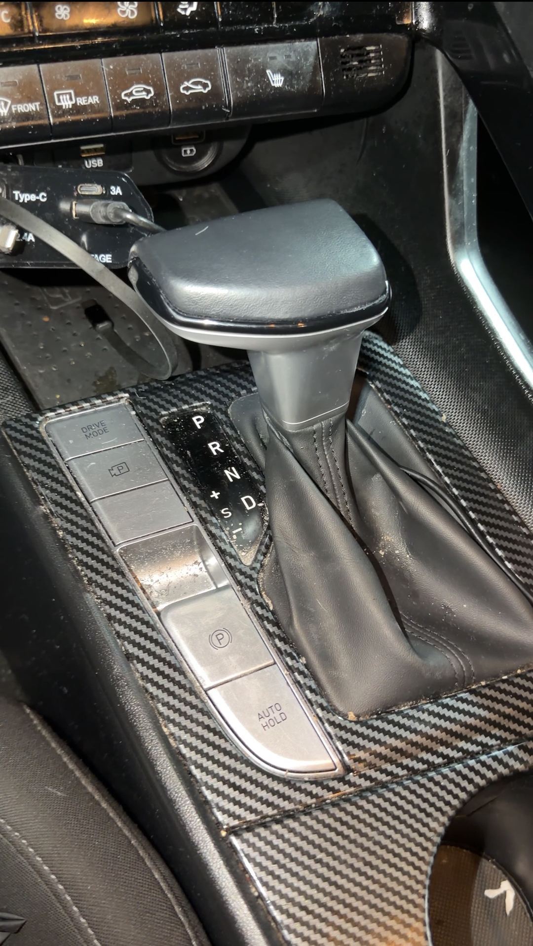 Hyundai Elantra shifter and carbon-look console trim with crumbs before cleaning