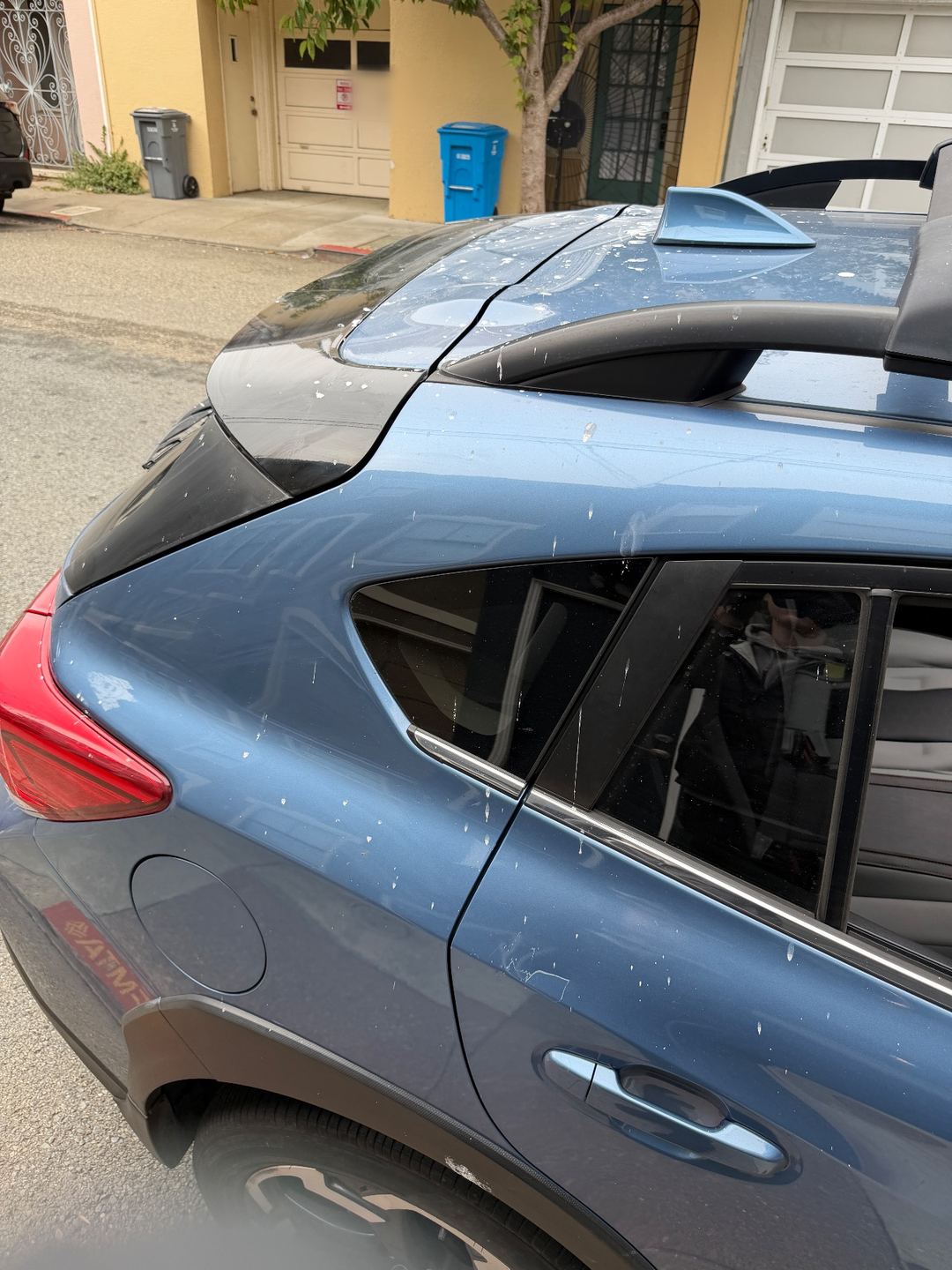 Rear quarter and roof of a blue Subaru Crosstrek before washing, spotted with white splatter