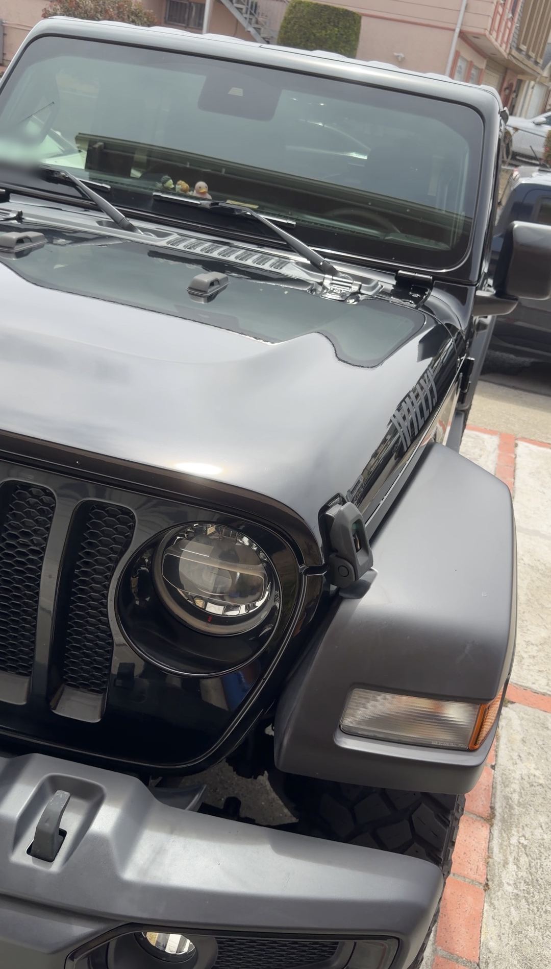Clean black Jeep Wrangler grille, round headlight and hood after cleaning