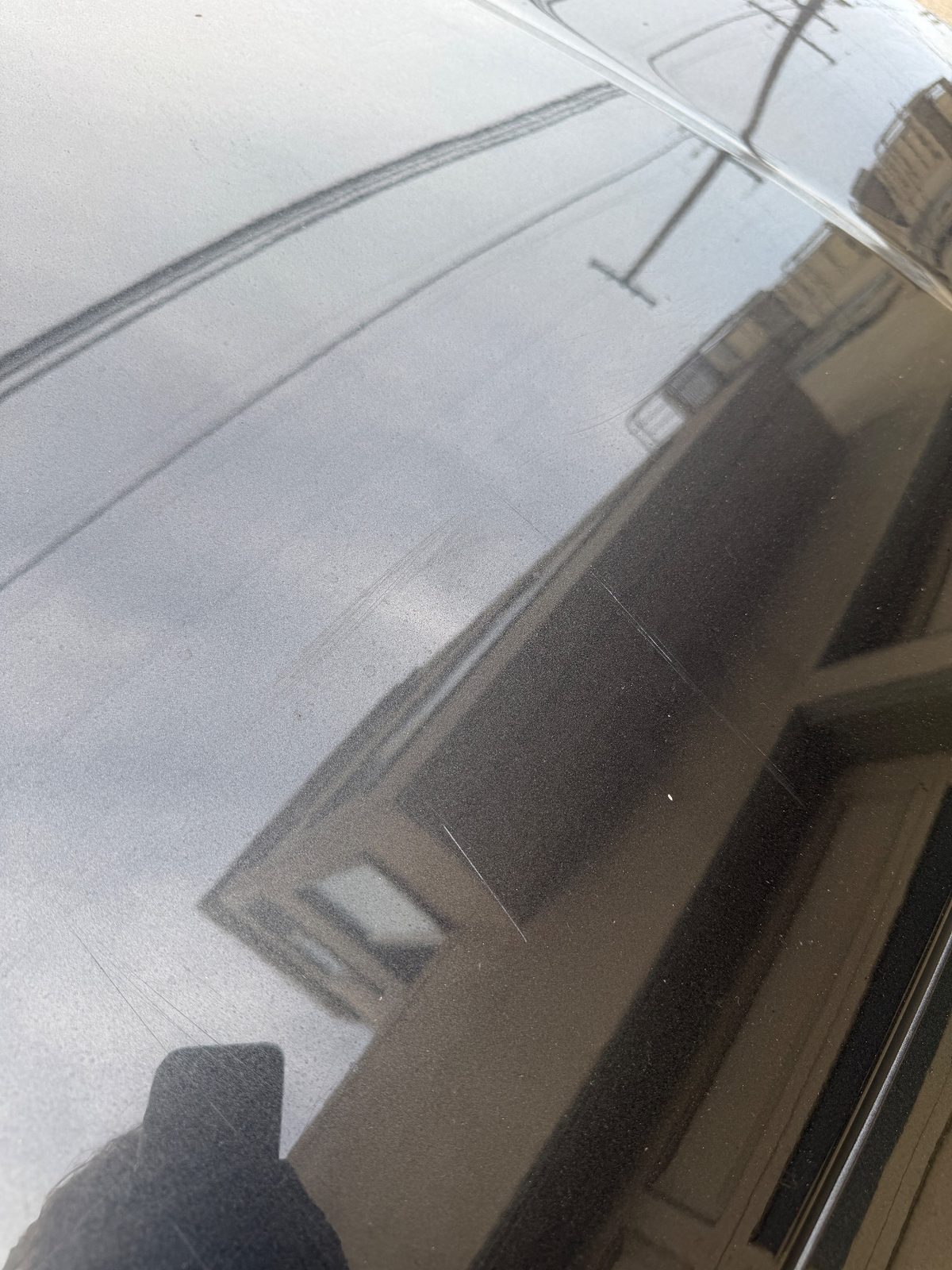 Close-up of fine hairline scratches on the hood paint of a grey Hyundai Santa Fe before detailing
