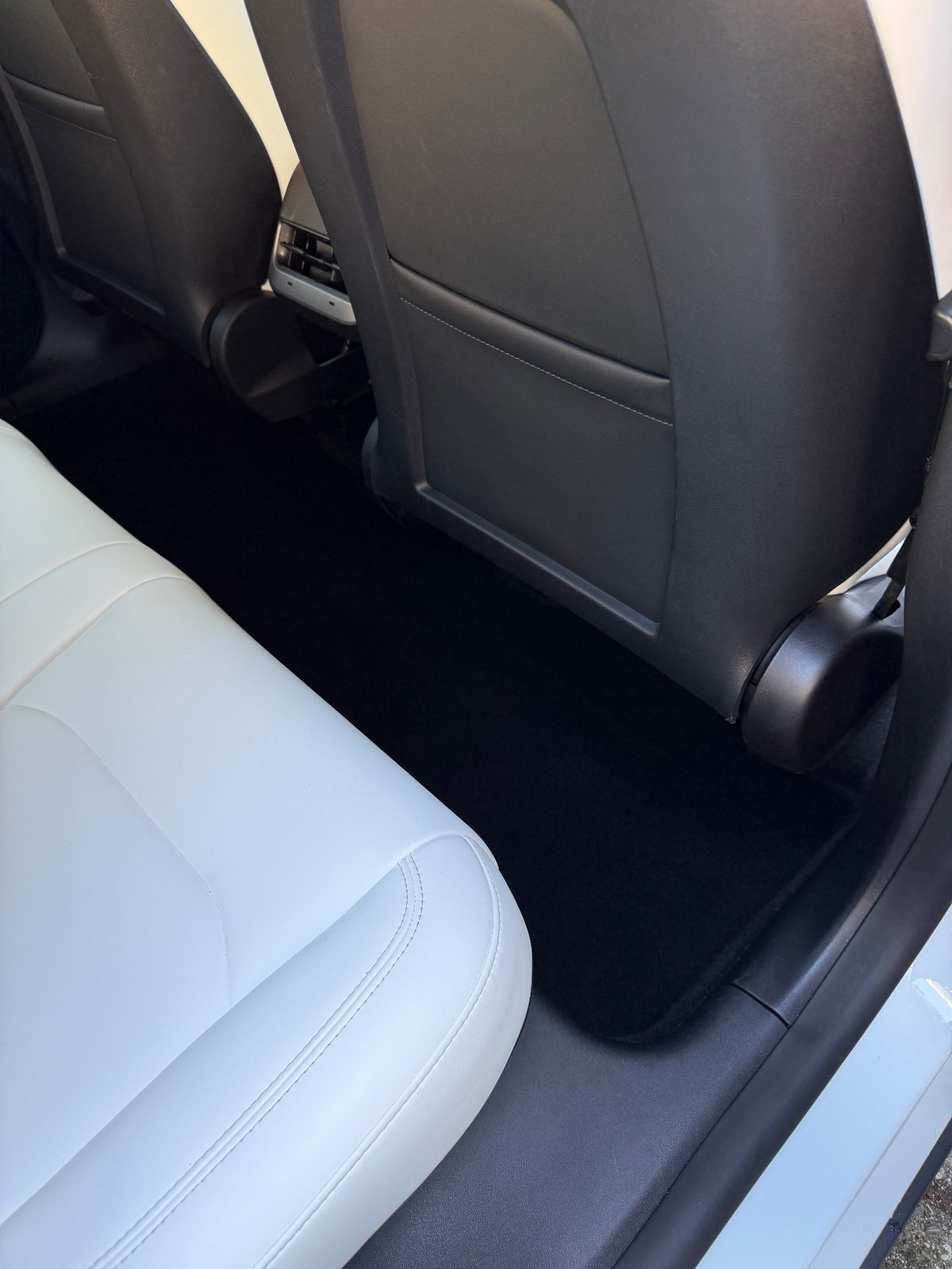 Clean rear passenger-side footwell of a Tesla Model Y after detailing