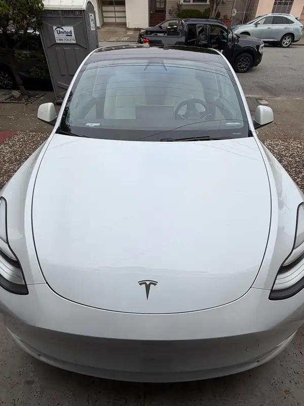 Front of a white Tesla Model Y after detailing, with a clean hood and windshield