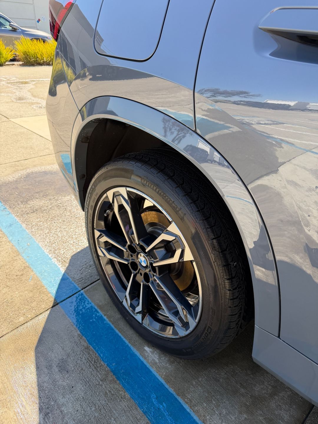 Rear wheel of a grey BMW X1 after washing, tyre dressed