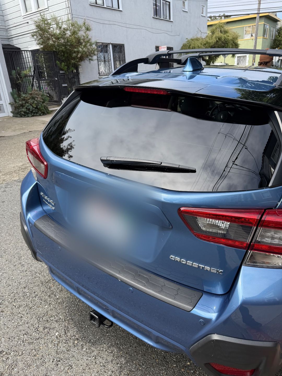 Rear hatch of a blue Subaru Crosstrek after washing, the white splatter gone from the spoiler