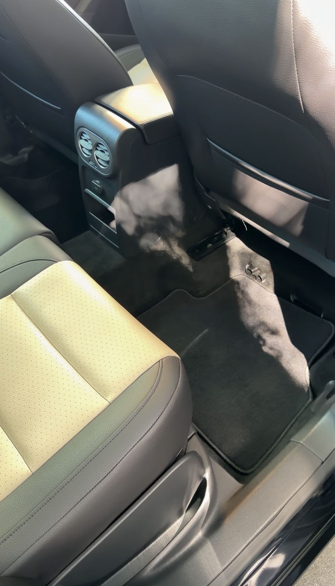 Passenger-side rear footwell of a black VW Tiguan after detailing, the rear mat clean.