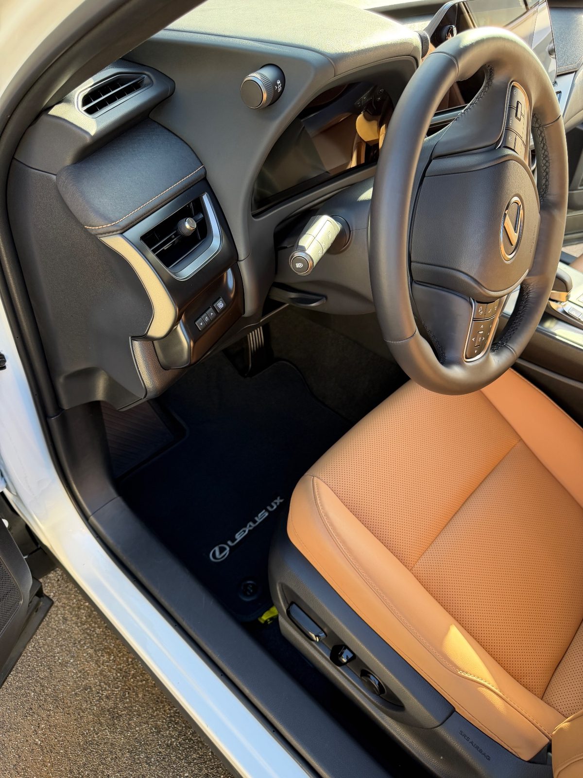 Clean driver footwell of a white Lexus UX after detailing, mat free of debris