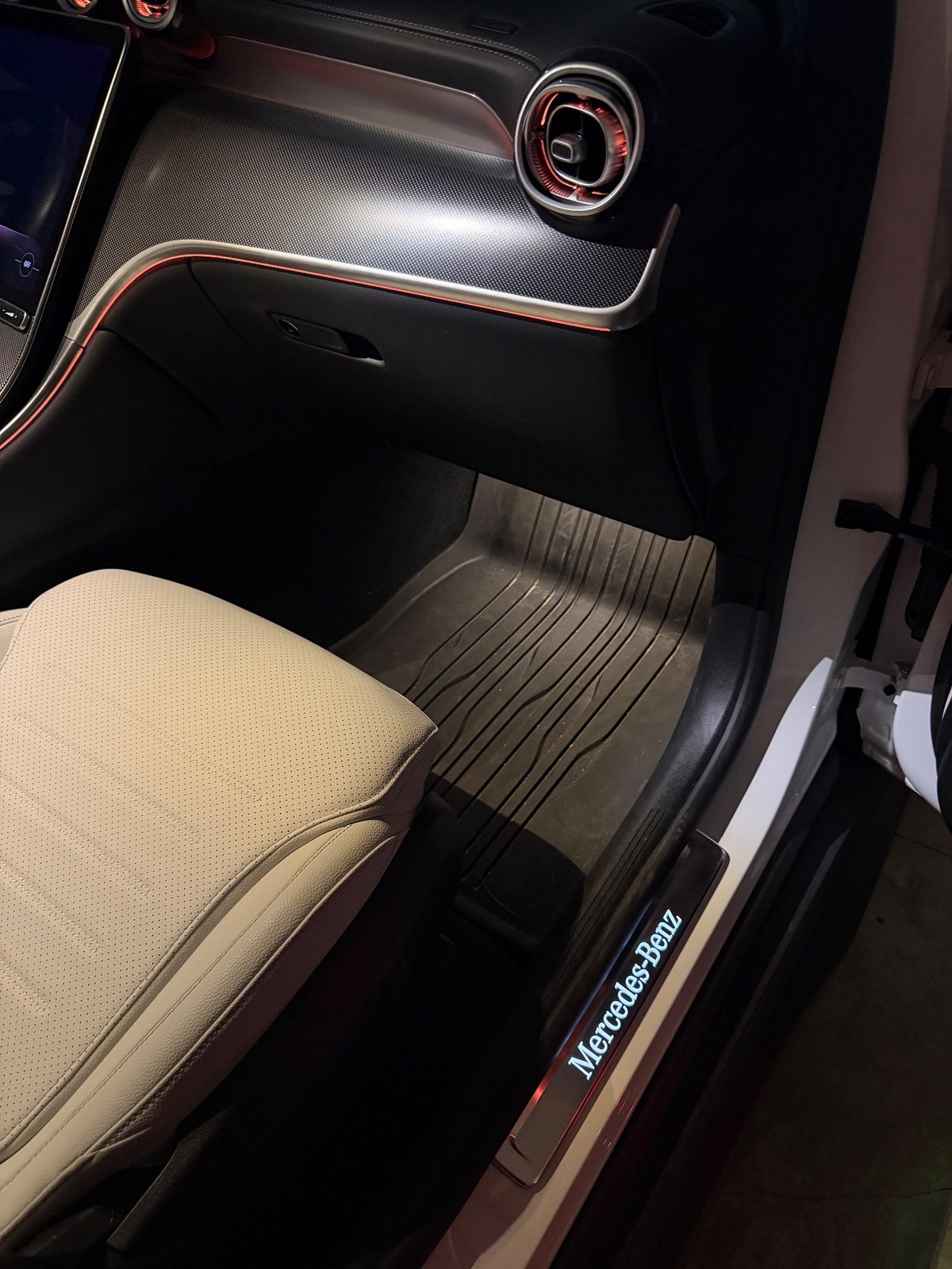 Front passenger footwell of a white Mercedes GLC before detailing, dusty rubber mat