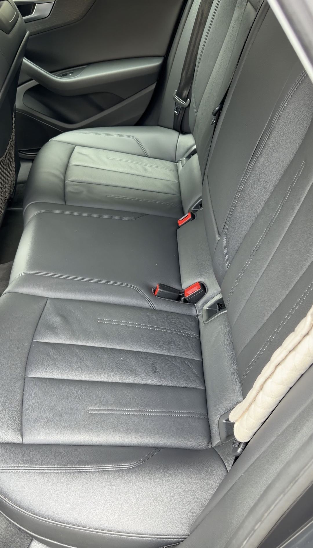 Clean black leather rear bench of an Audi A4 seen from the driver-side rear door