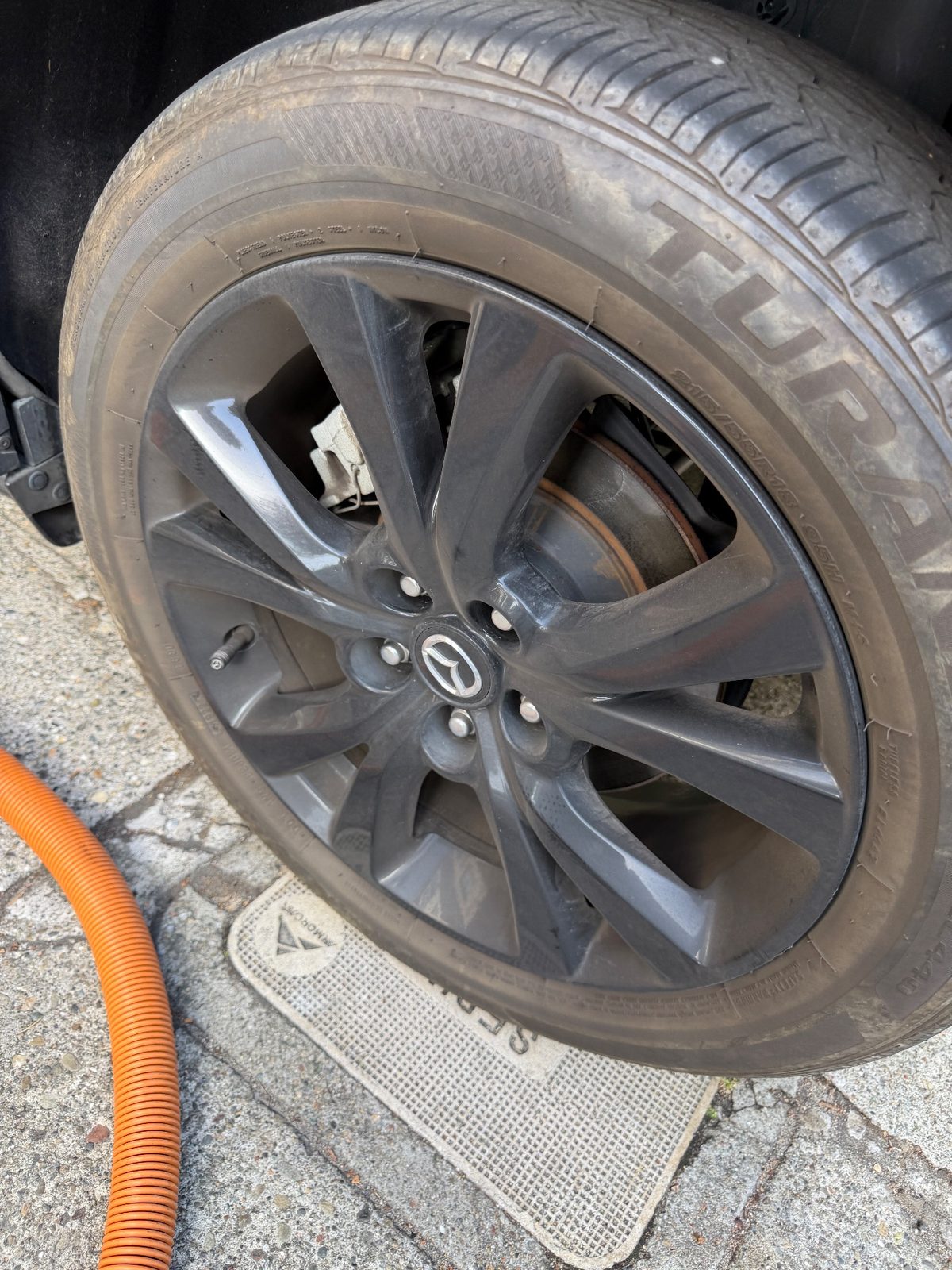 Dirty alloy wheel of a grey Mazda CX-30 before cleaning, brake dust on the spokes