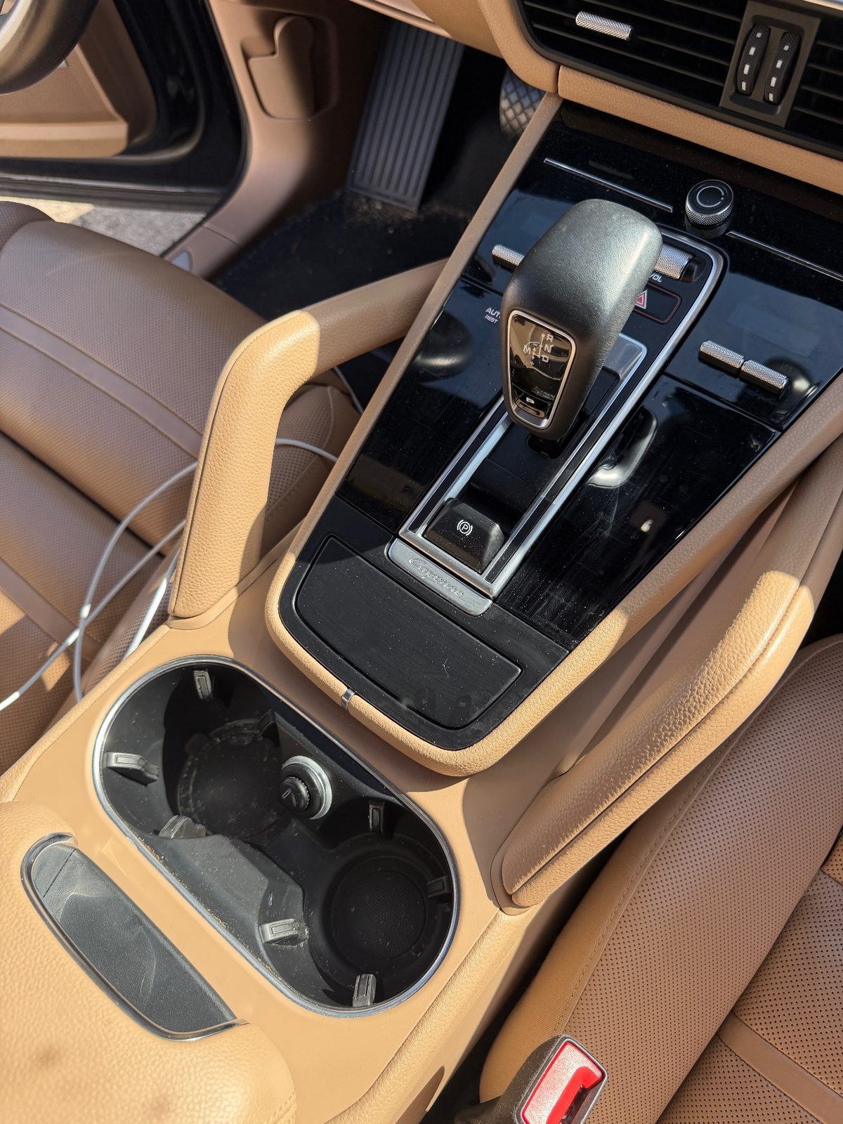 Centre console of a dark blue Porsche Cayenne before cleaning, dusty gloss trim and grimy cupholders
