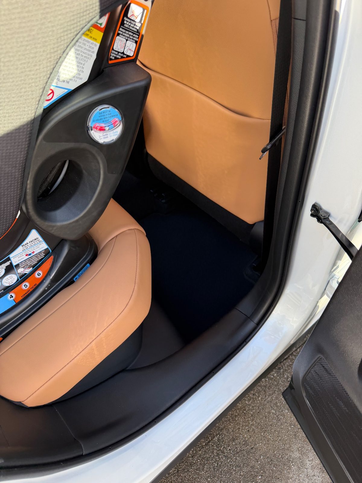 Clean rear footwell of a white Lexus UX beside a child seat after detailing