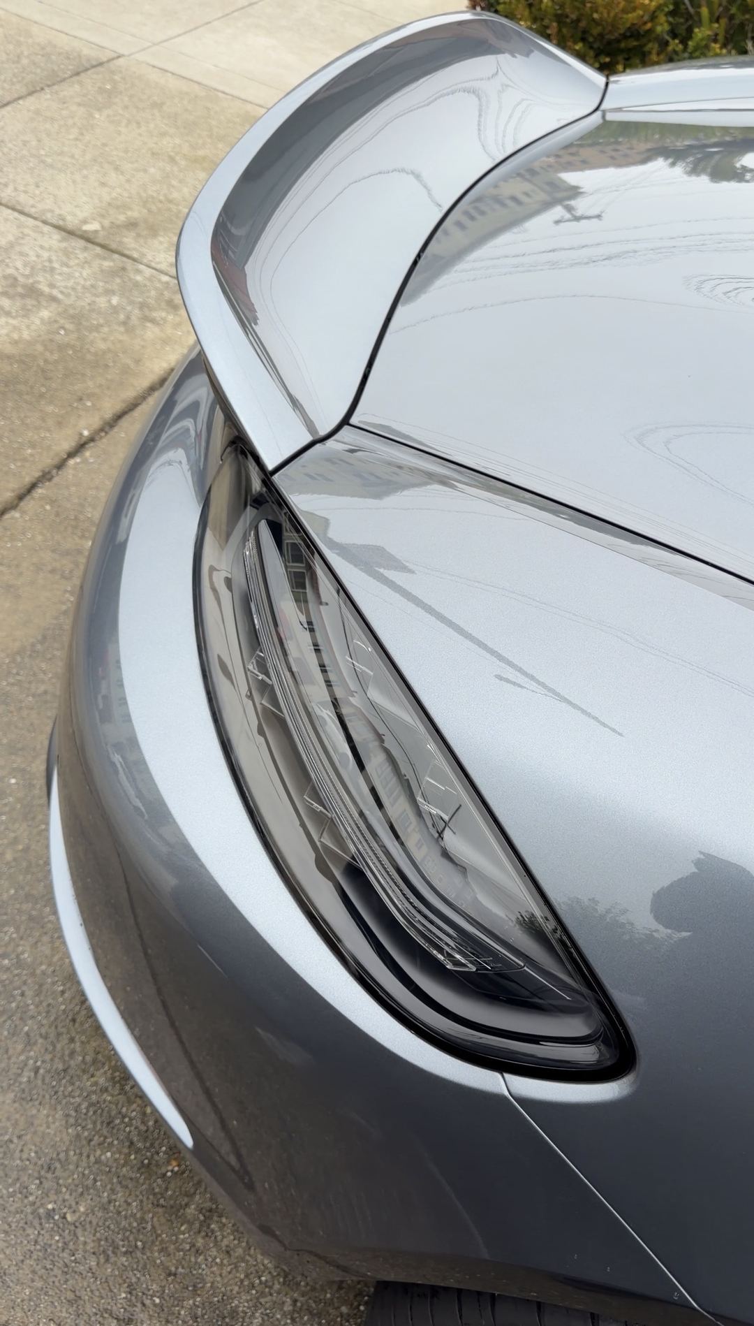 Close-up of the clean headlight and front wing of a grey Porsche 718 Spyder RS after a mobile detail.