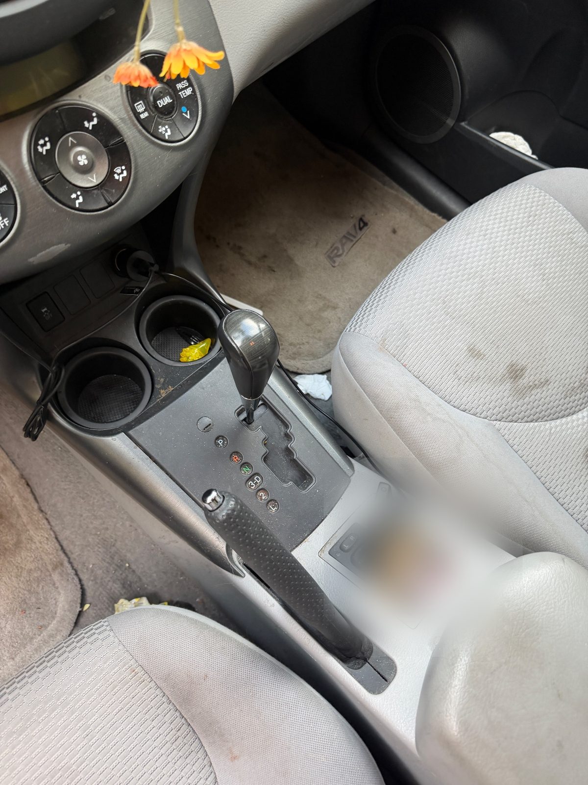Centre console of a 2011 Toyota RAV4 before detailing, wrappers in the cupholders and crumbs on the mat