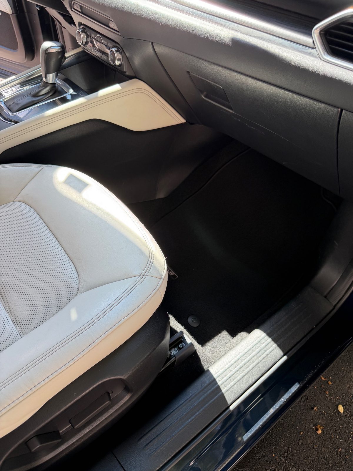 Clean front passenger footwell of a dark blue Mazda CX-5 after detailing, vacuumed mat