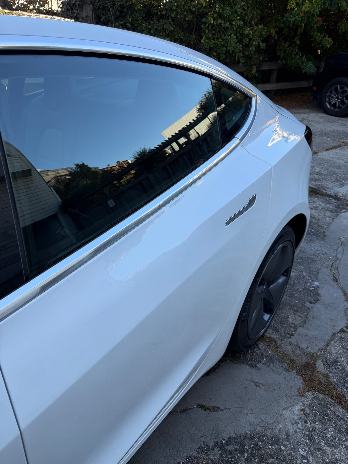 Rear door of a white Tesla Model 3 after detailing, glossy white paint