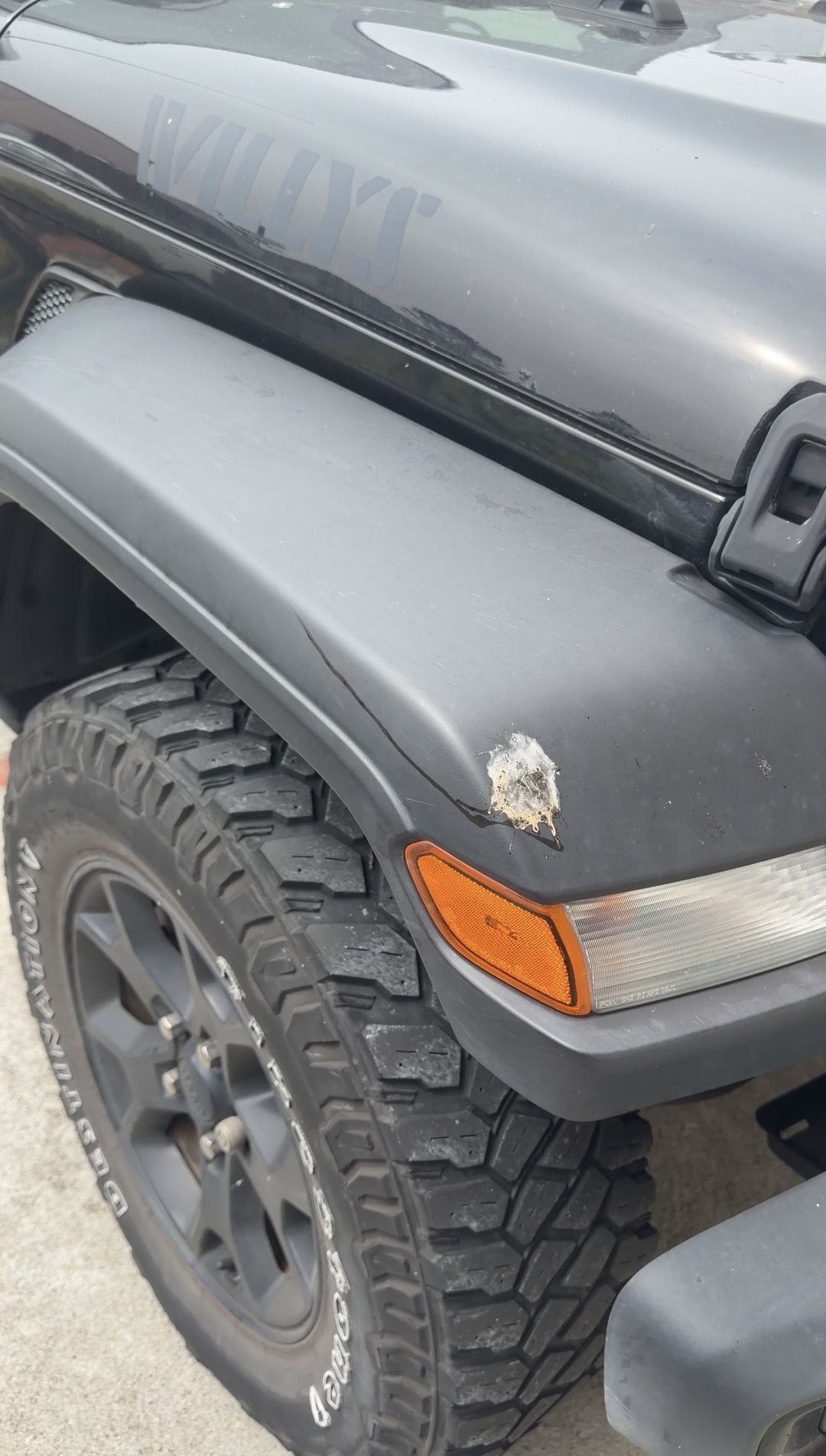 Jeep Wrangler front fender flare with an existing chip beside the marker light, before cleaning