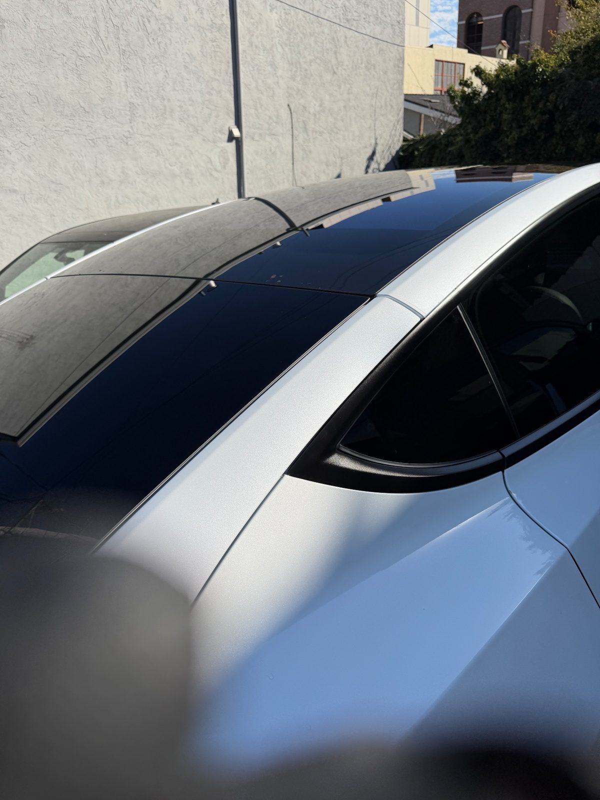 Clean glossy glass roof and rear pillar of a white Tesla Model Y after detailing