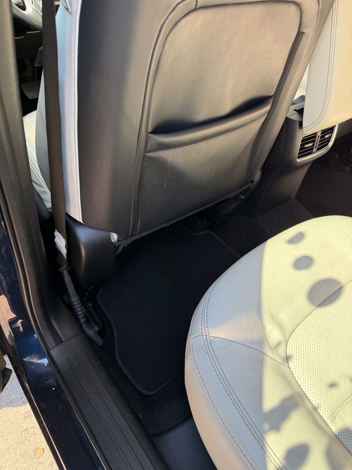 Clean rear footwell of a dark blue Mazda CX-5 after detailing, vacuumed mat and wiped seat-back leather