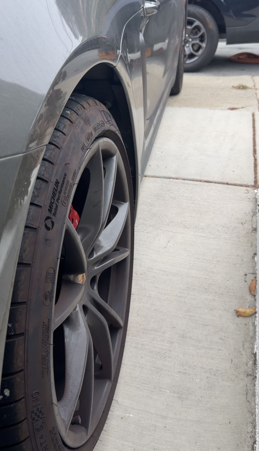 Contaminated tyre shoulder and dusty wheel of a Porsche 718 Cayman S seen from a low angle before cleaning.