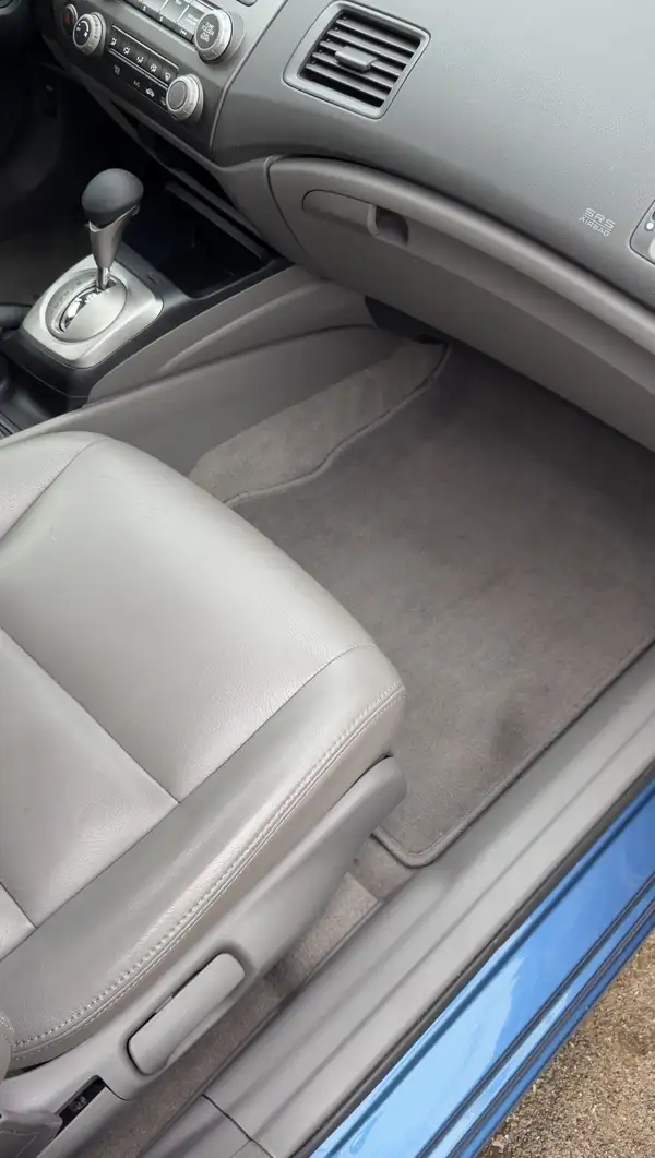 Cleaned front passenger footwell of a Honda Civic, carpet mat vacuumed and the door sill wiped.