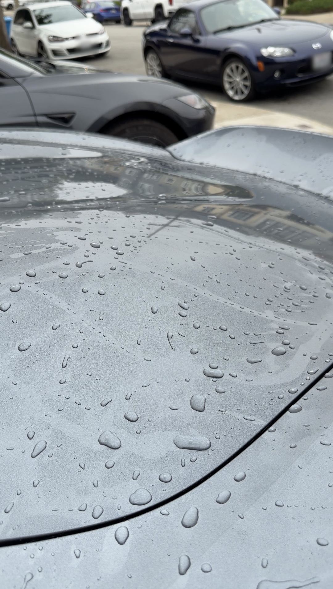 Water beading on the freshly rinsed grey paint of a Porsche 718 Spyder RS.