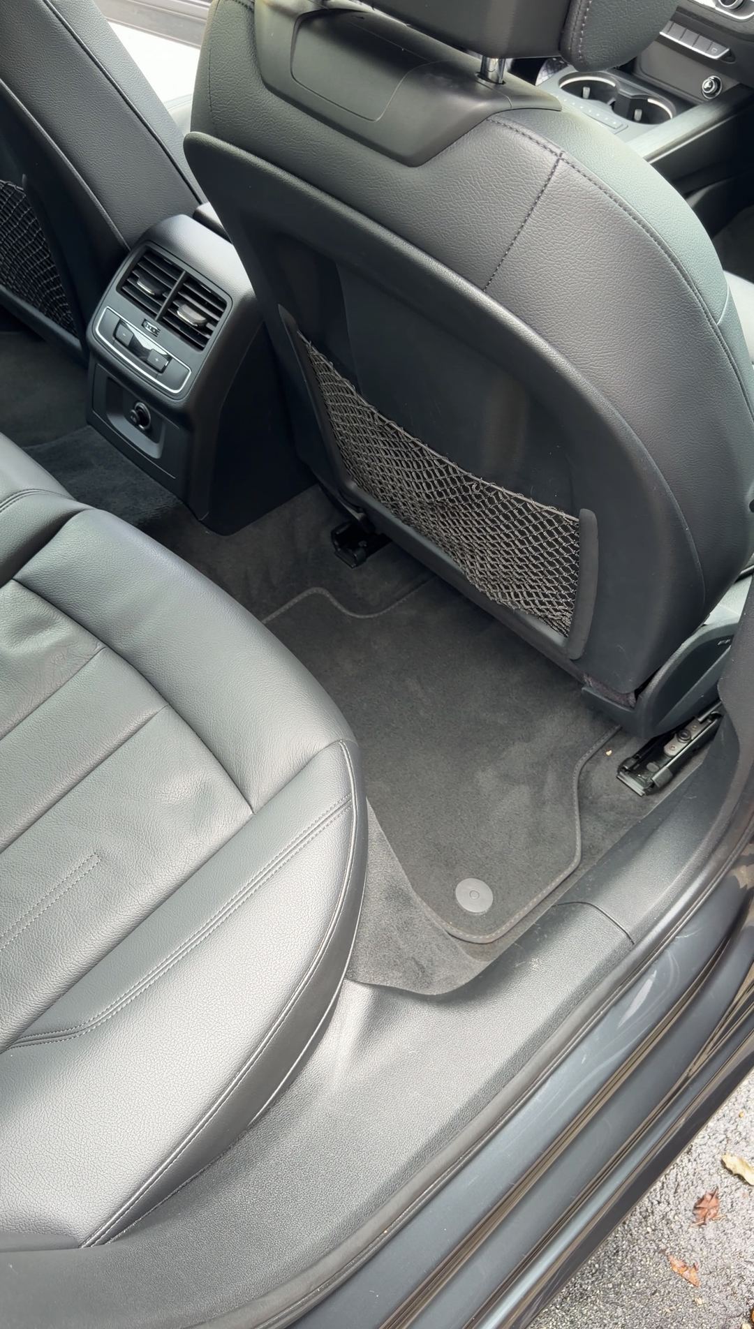 Vacuumed rear floor mat behind the passenger seat of an Audi A4 with black leather seats