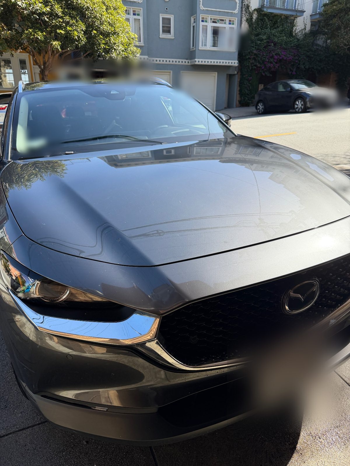Front three-quarter of a grey Mazda CX-30 after a wash on a San Francisco street