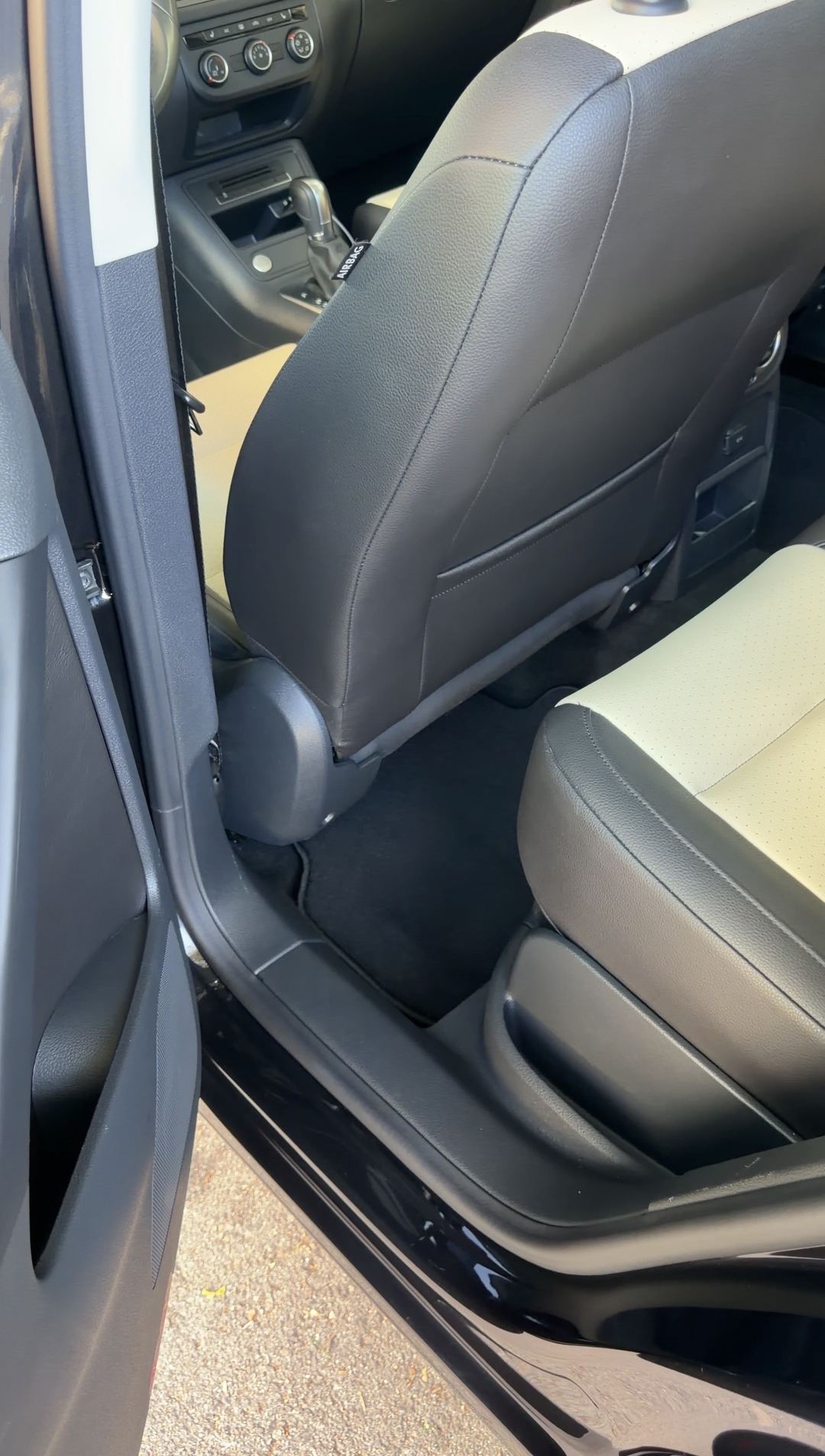 Driver-side rear footwell of a black VW Tiguan after detailing, mat and carpet clean.