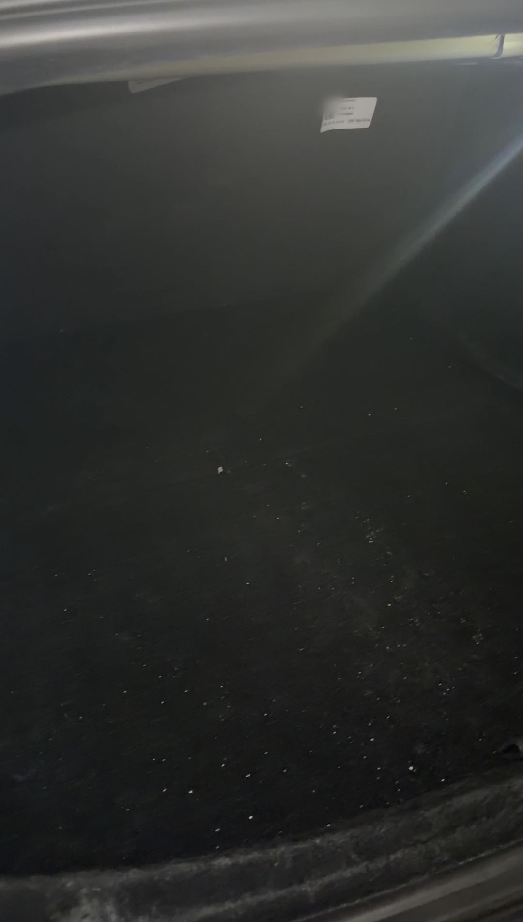 Boot floor of a Tesla Model 3 before detailing, carpeted with white lint and crumbs