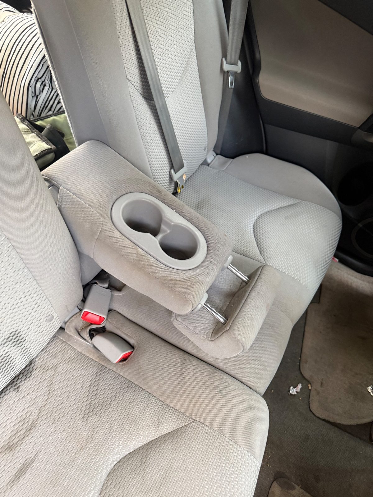 Rear armrest and seat of a 2011 Toyota RAV4 before detailing, stains and wrappers
