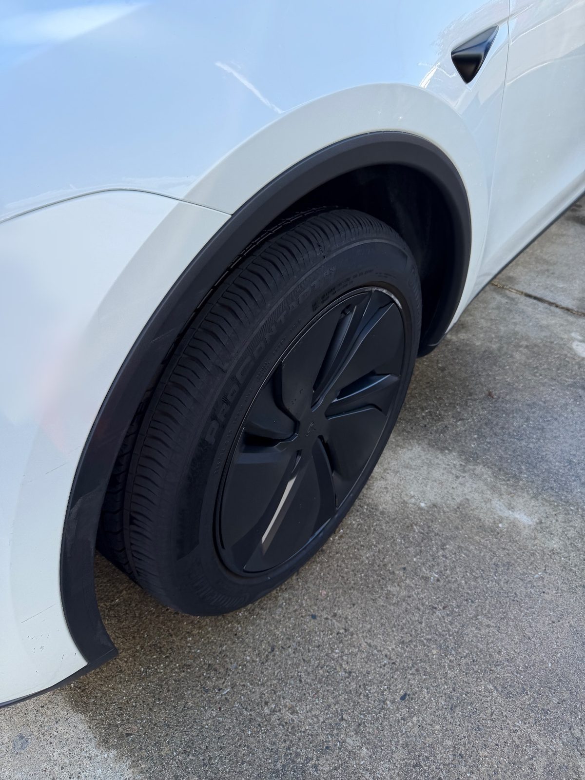 Clean black aero wheel and dressed tyre on a white Tesla Model Y after detailing