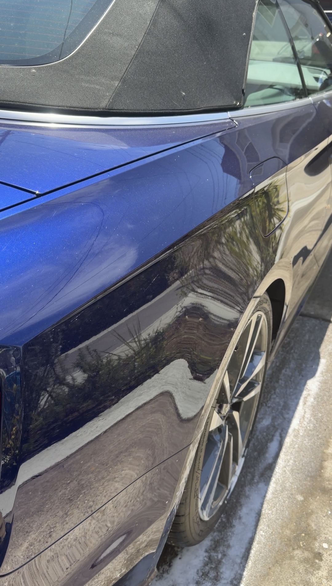 Rear quarter of a blue Audi S5 Cabriolet with light dust specks and wet pavement below