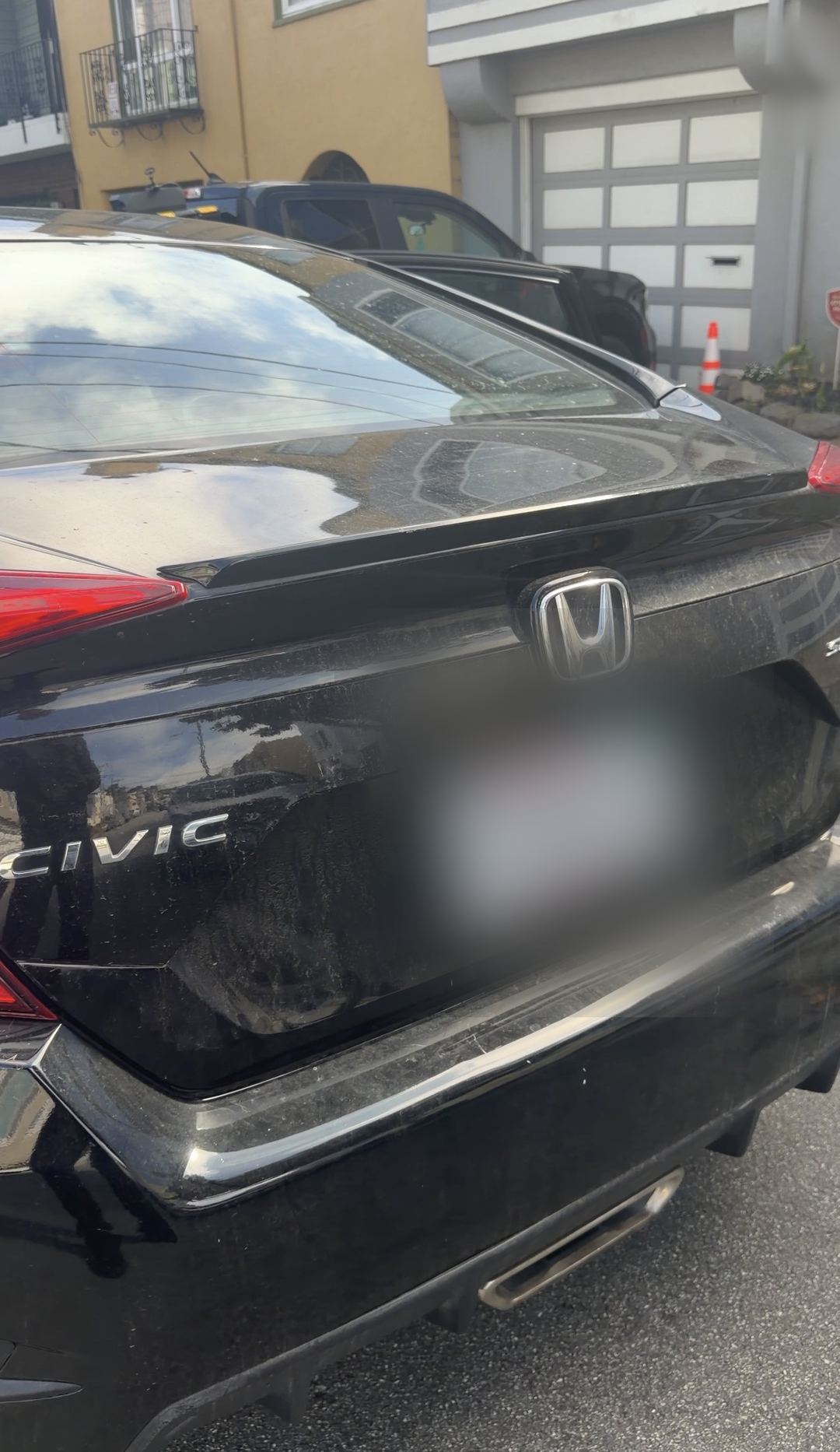 Dusty trunk lid of a black Honda Civic before the exterior wash
