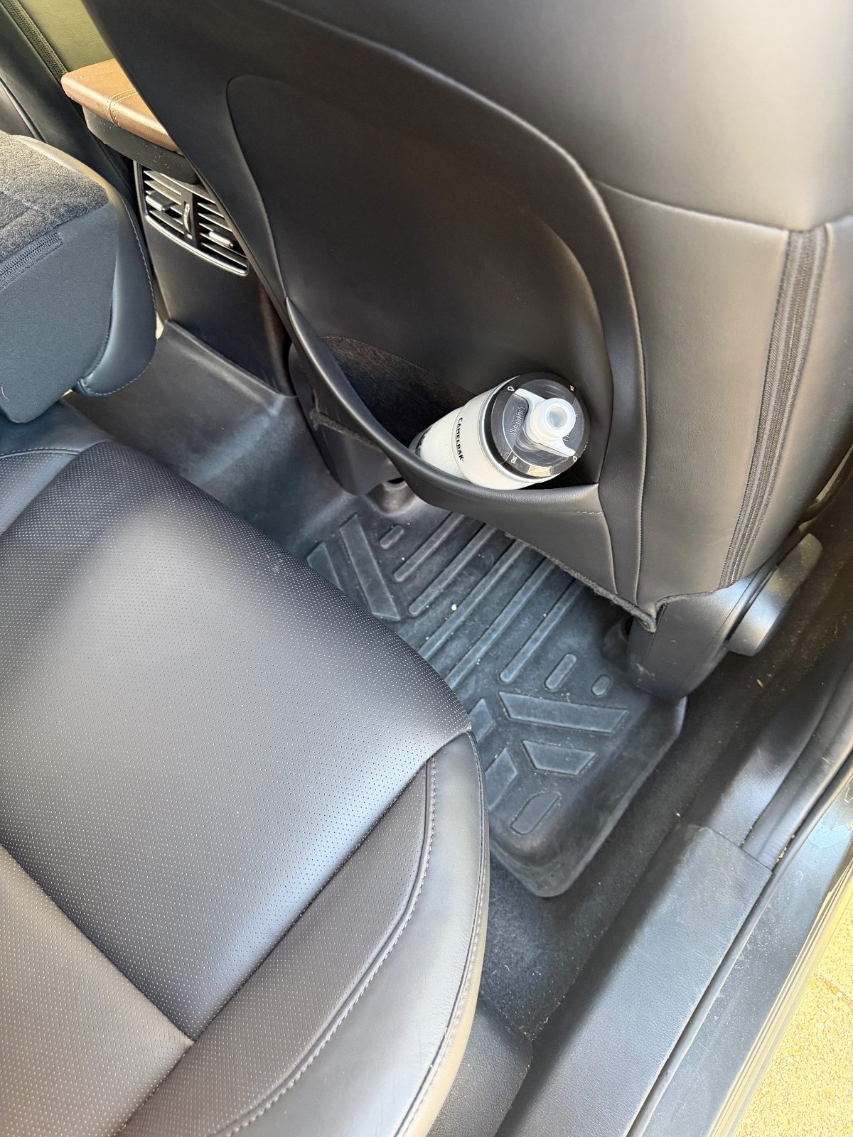 Rear footwell of a grey Mazda CX-30 before cleaning, floor liner grimy with dirt and debris