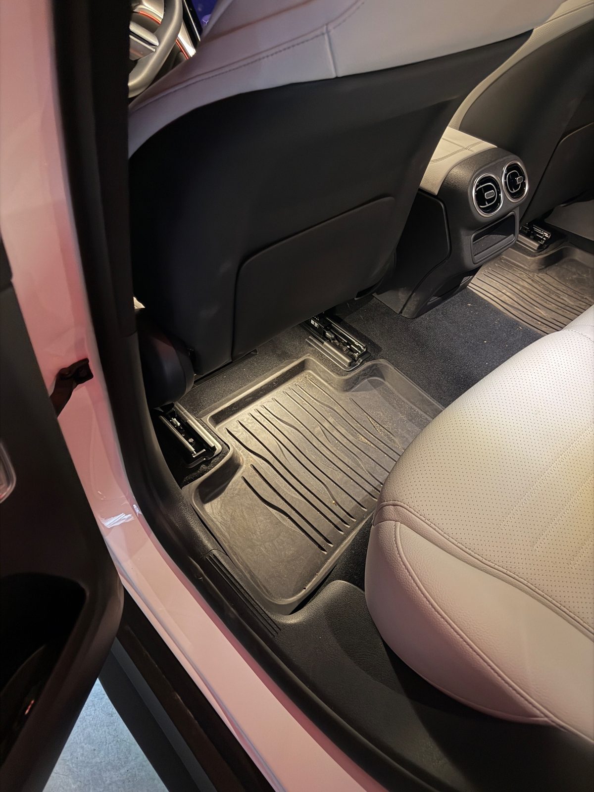 Rear footwell of a white Mercedes GLC before detailing, rubber mat full of dust and grit