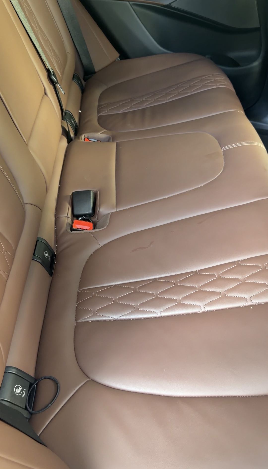 Rear bench of a BMW X5 in cognac quilted leather before cleaning, with a dark smear on the centre cushion panel