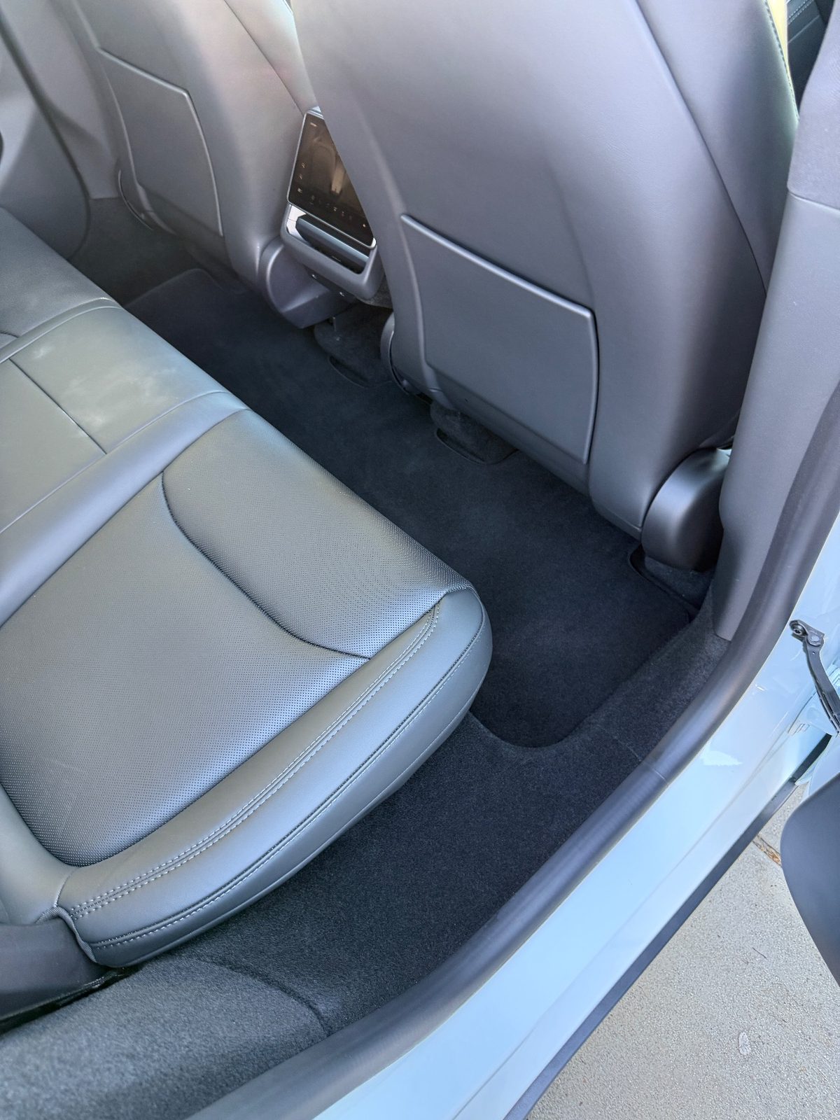 Clean rear footwell of a white Tesla Model Y after vacuuming