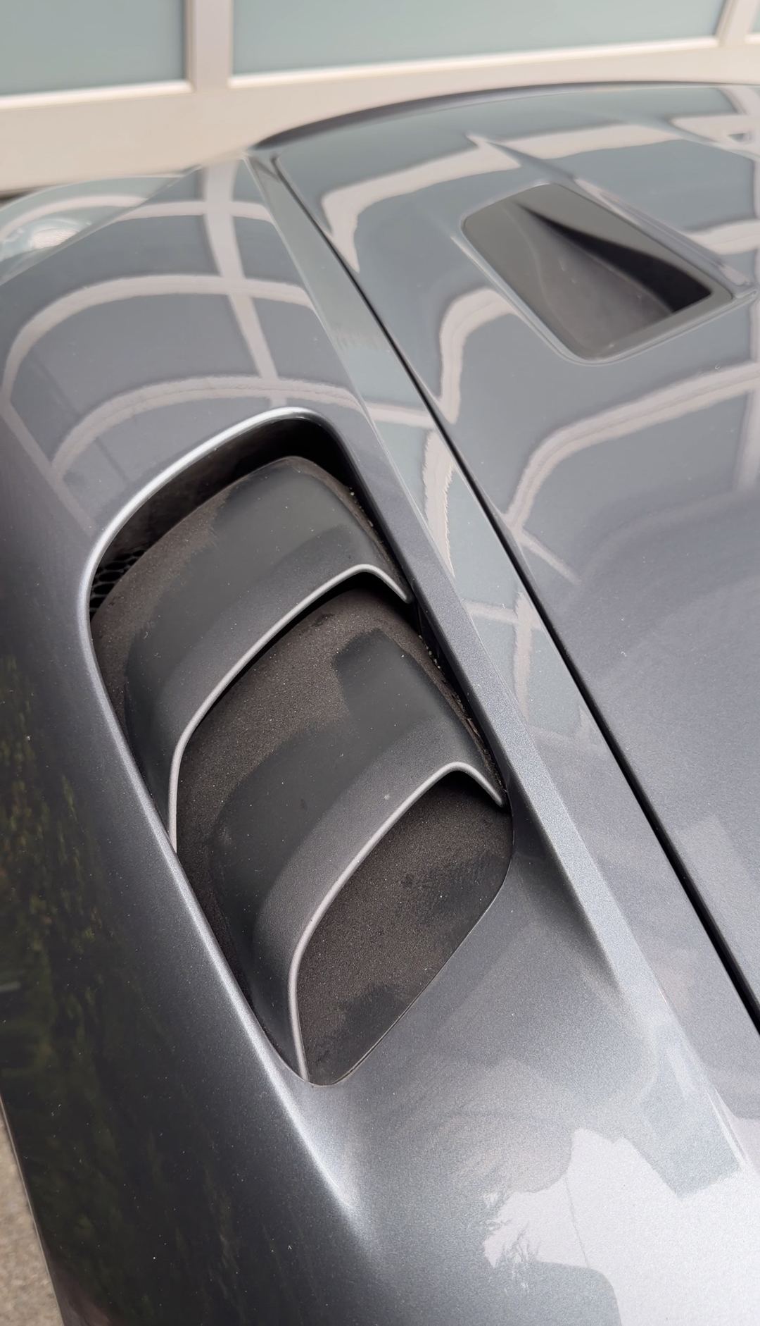 Close-up of the black louvred engine air intake on a grey Porsche 718 Spyder RS.