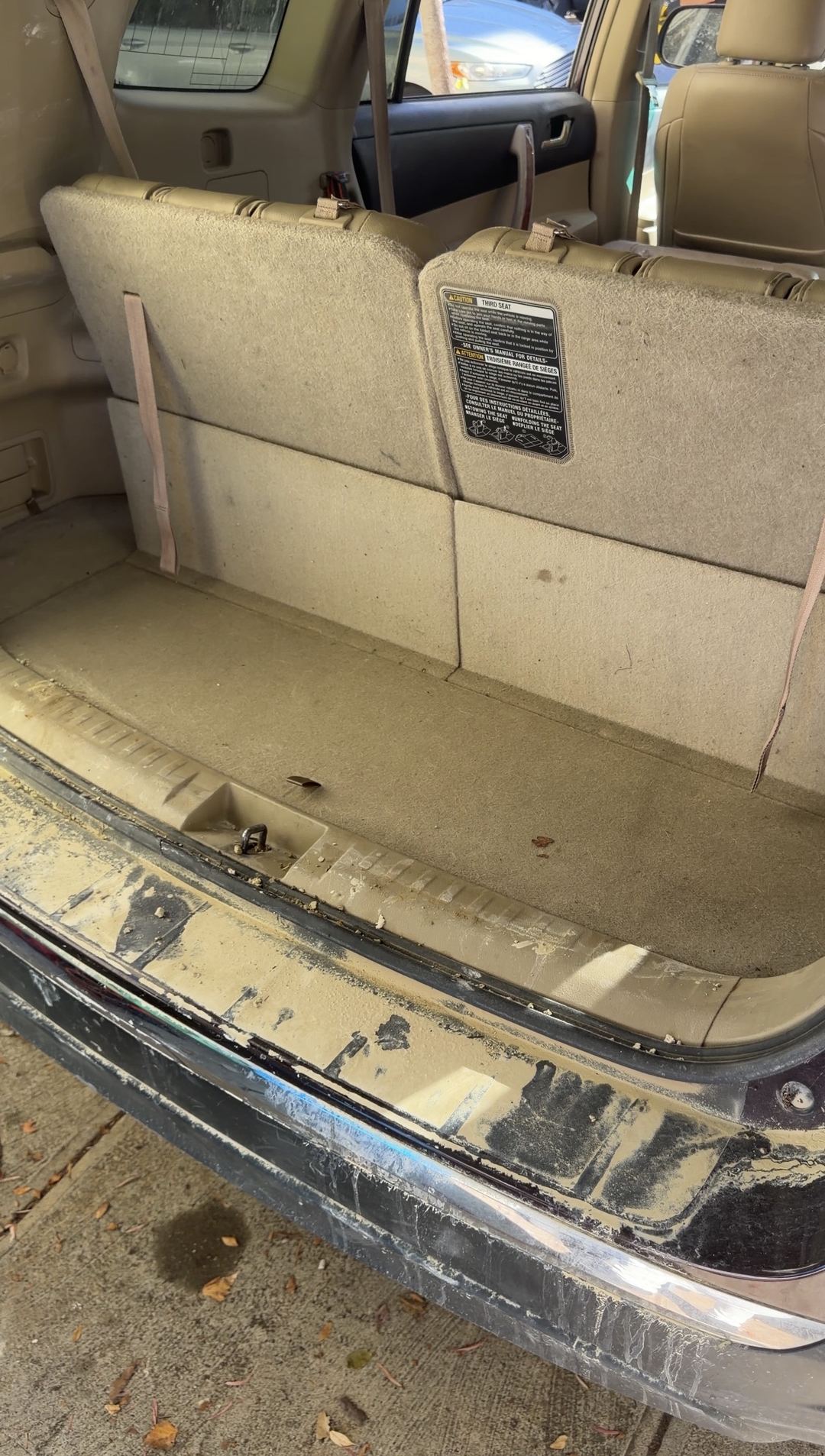 Cargo area of a Toyota Highlander with dusty carpet and a rear sill caked in pale dust