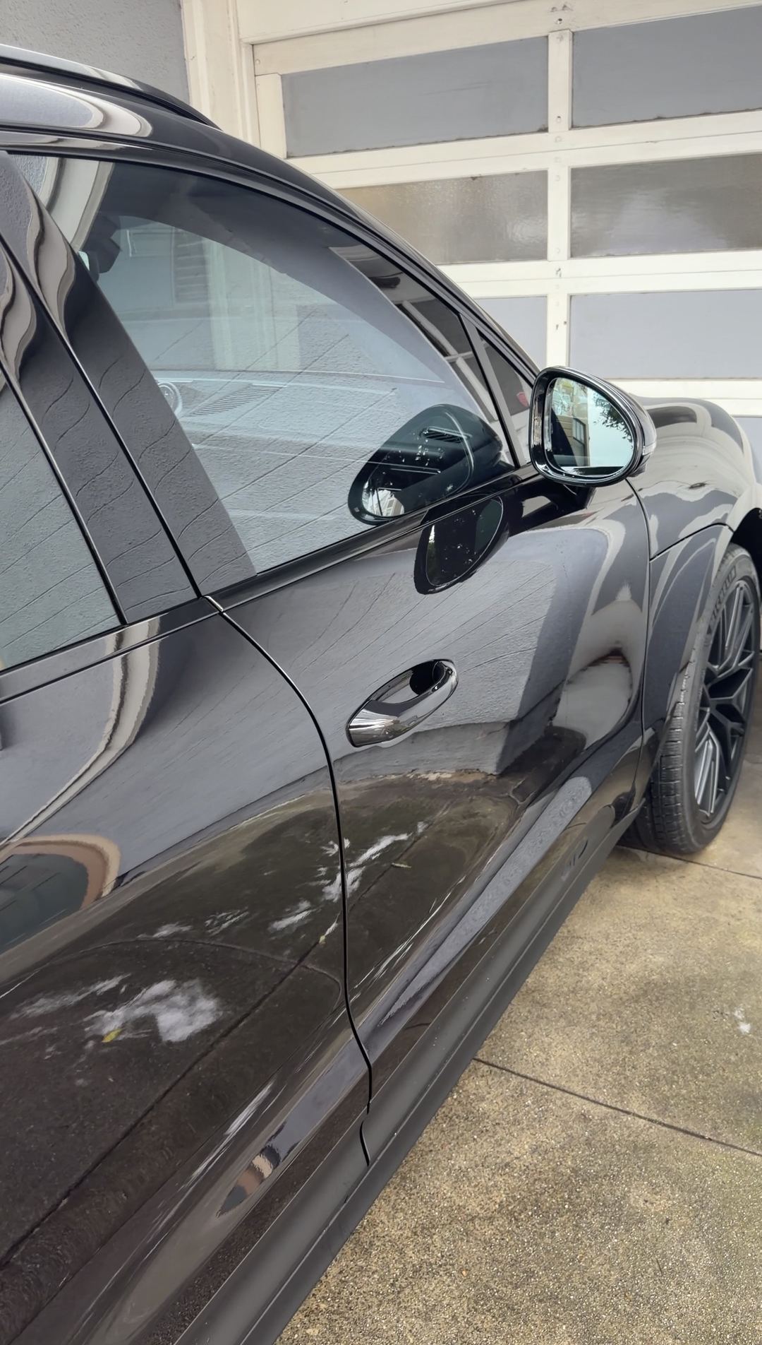 Dried splatter and road film on the driver's side doors of a black Porsche Macan GTS before an SF City Wash detail.